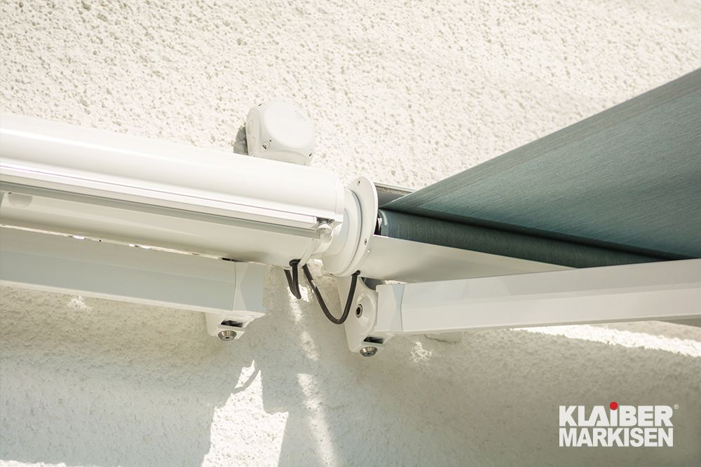 Eine weiße Markise wird von der Firma Klaider Markisen an einer Wand befestigt.