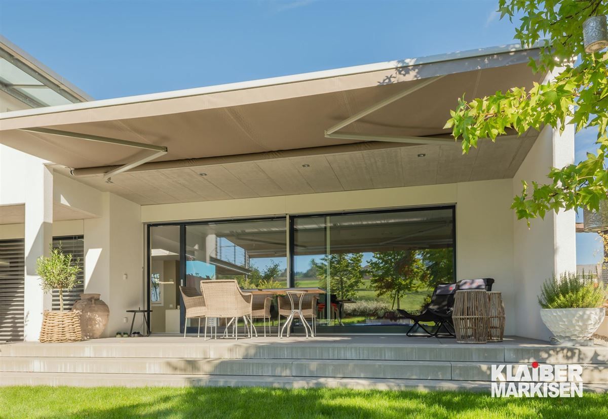 Ein großes Haus mit einer großen Markise über der Terrasse.