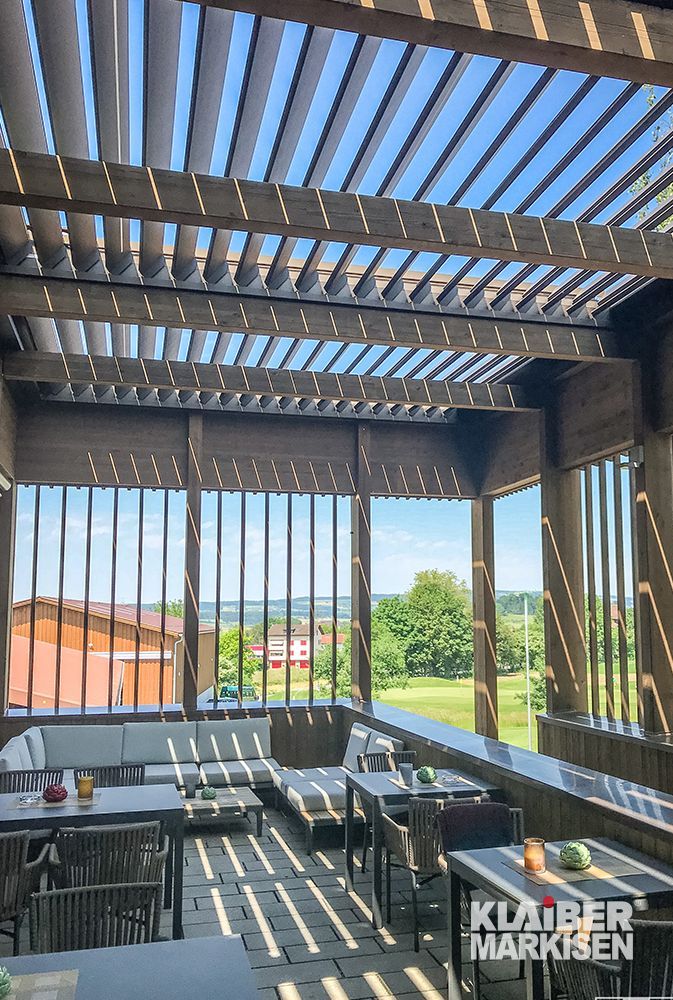 Eine Terrasse mit Tischen und Stühlen unter einer Pergola