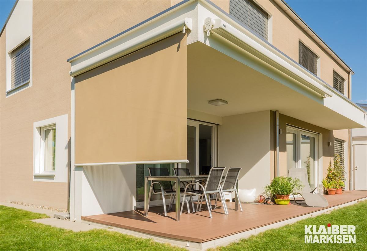Ein Haus mit einer Terrasse mit einem Tisch und Stühlen darauf
