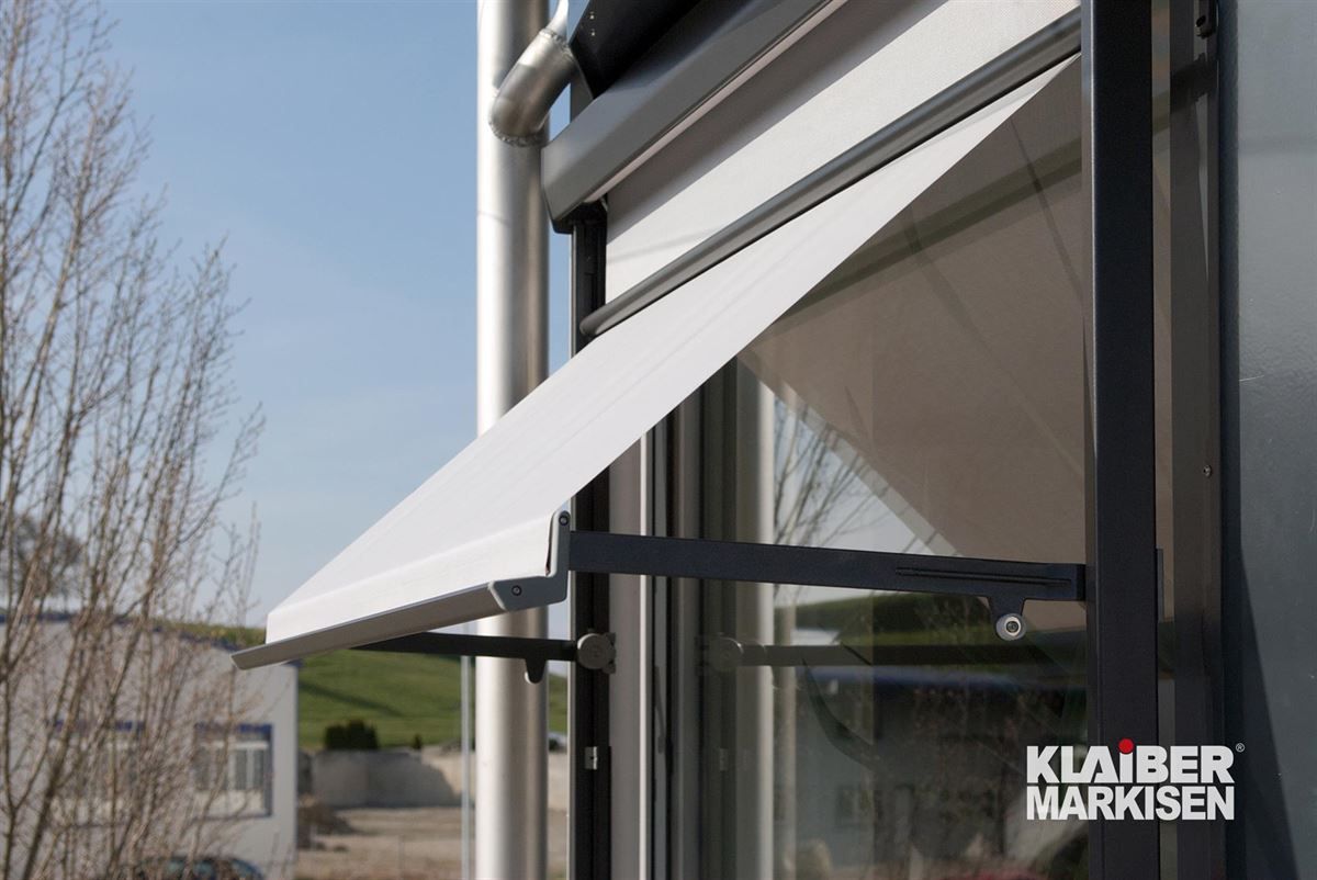 Ein Fenster mit einer weißen Markise, auf der „Kliber Markisen“ steht