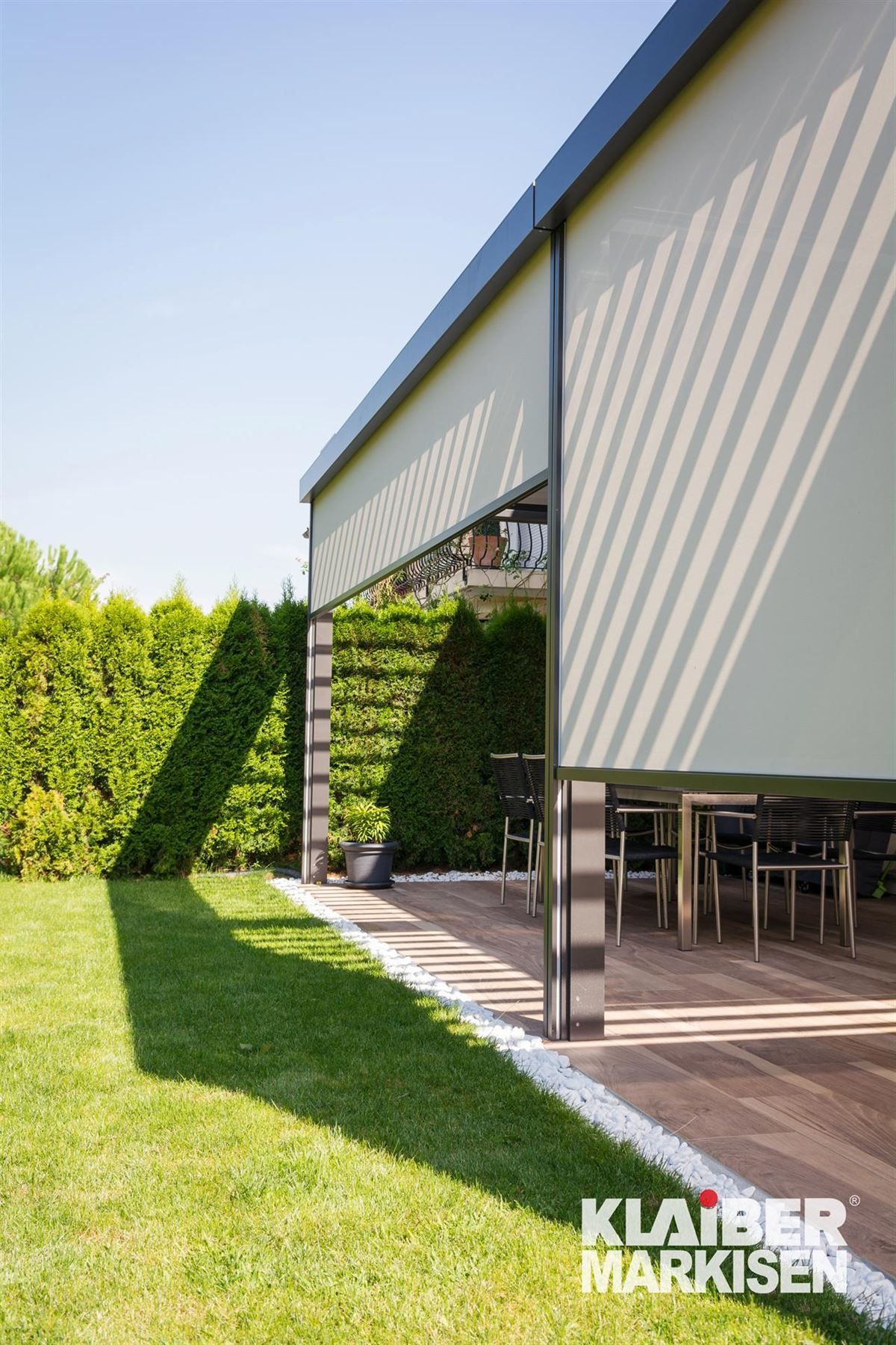 Eine Terrasse mit Tisch und Stühlen unter einem Baldachin in einem Hinterhof.
