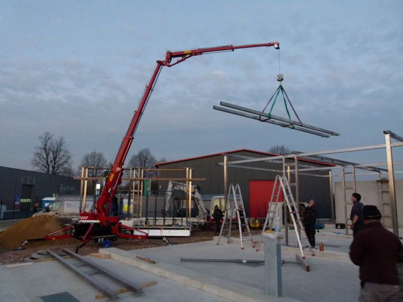 Ein roter Kran hebt ein großes Stück Metall