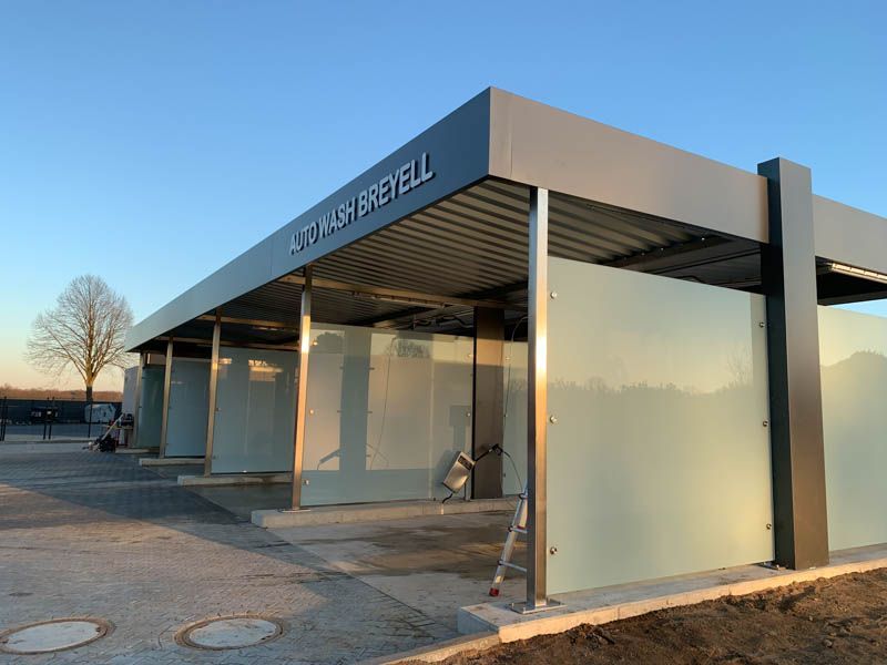 Eine Autowaschanlage mit Überdachung und davor liegender Leiter.