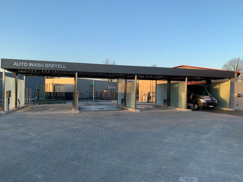 In einer Autowaschanlage ist ein Auto unter einem Vordach geparkt.