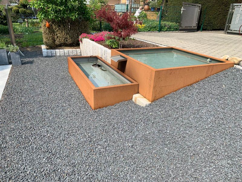 Ein paar Pflanzkübel stehen auf einer Kiesauffahrt.