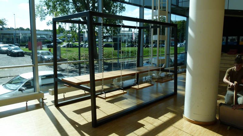 Ein Mann sitzt auf einer Bank vor einem Schaukeltisch.