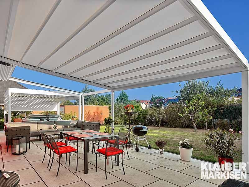 Eine Terrasse mit Tisch und Stühlen unter einer Pergola.