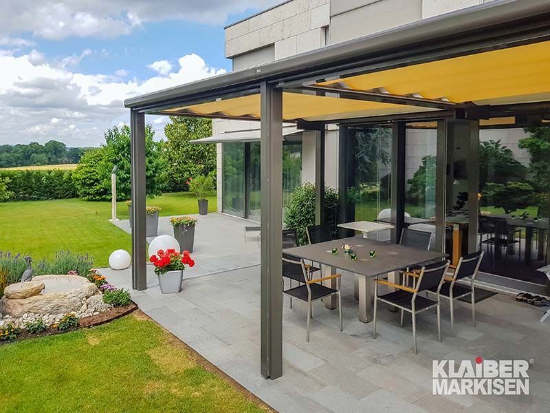 Eine Terrasse mit Tisch und Stühlen unter einem Baldachin.