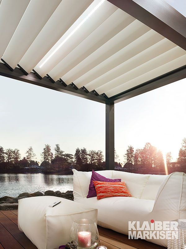 Ein weißes Sofa steht unter einer Pergola mit Blick auf einen See.