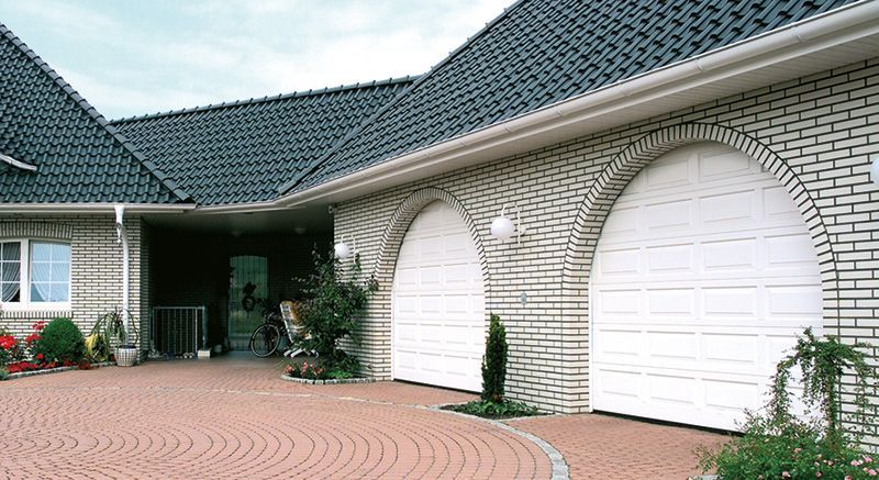 Ein großes weißes Backsteinhaus mit einer gemauerten Auffahrt davor