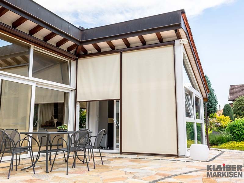 Ein Haus mit einer Terrasse und einem Tisch und Stühlen darauf.