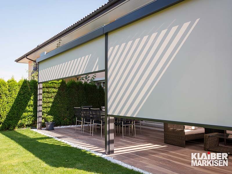 Eine Terrasse mit Esstisch und Stühlen unter einer weißen Markise.