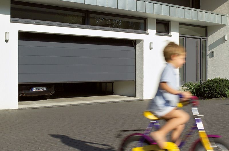 Ein Kind fährt Fahrrad vor einem Garagentor