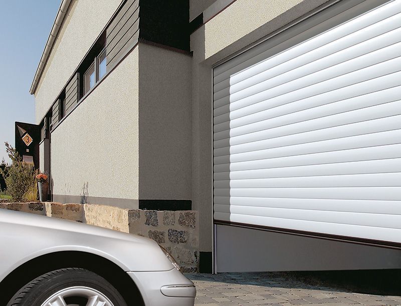 Ein silbernes Auto steht vor einem weißen Garagentor