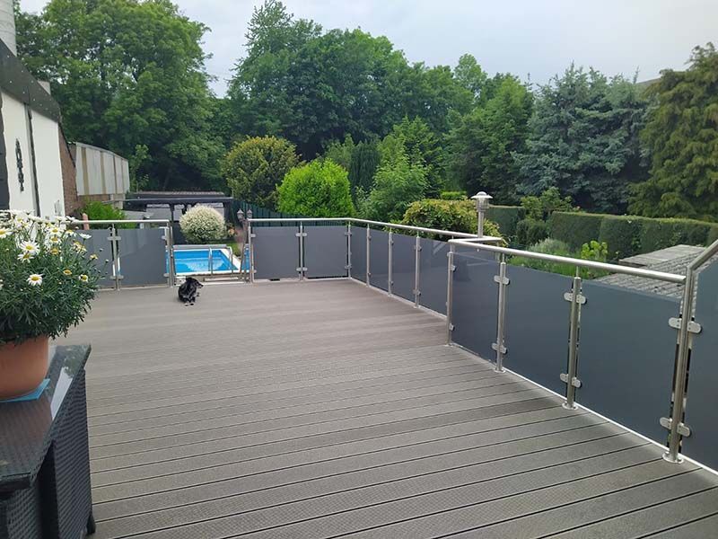 Ein Balkon mit Zaun und einem Swimmingpool im Hintergrund