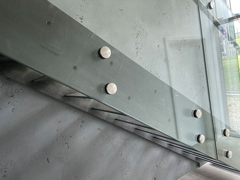 Eine Nahaufnahme eines Glasgeländers mit Schrauben darauf.