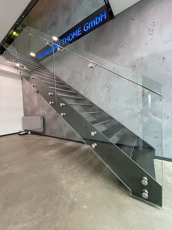 Eine Treppe mit einem Glasgeländer in einem Raum.
