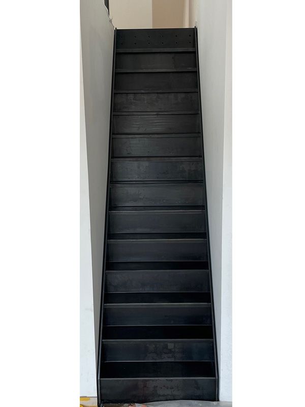 Eine schwarze Treppe, die zu einer weißen Wand hinaufführt.