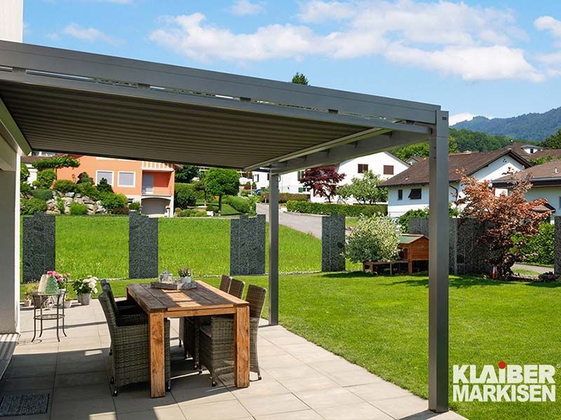 Eine Terrasse mit Tisch und Stühlen unter einer Pergola.
