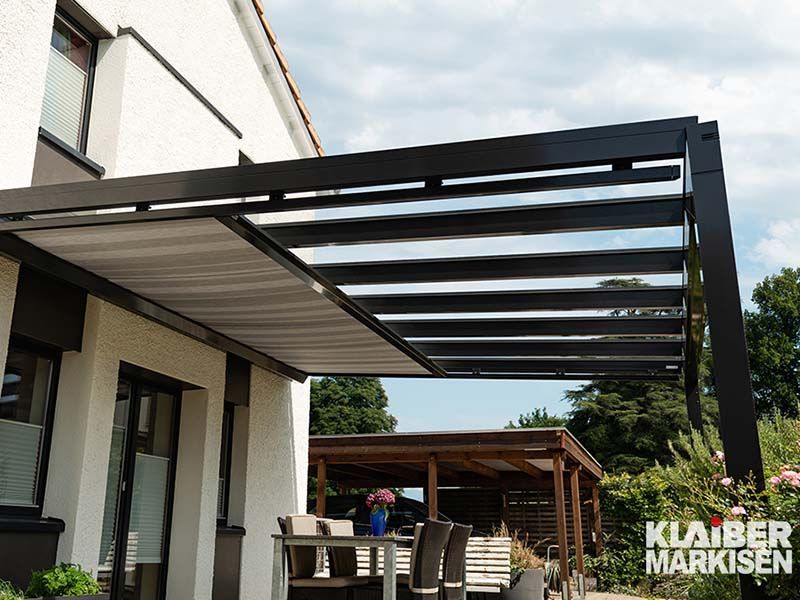 Eine Terrasse mit einer Pergola und einem Tisch und Stühlen darunter.