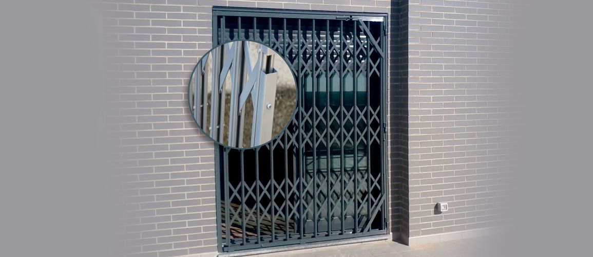 Una puerta de seguridad metálica retráctil de color oscuro instalada 