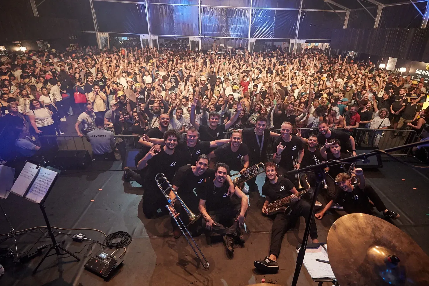 Groupe sur scène avec une grande foule, acclamant et applaudissant.