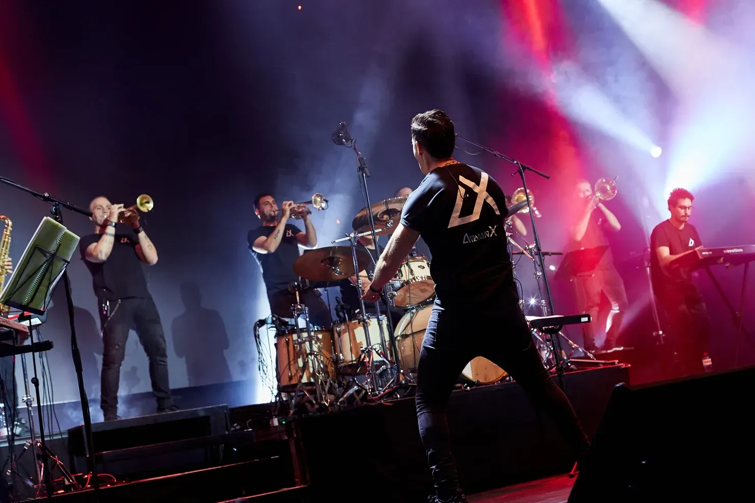 Groupe se produisant sur scène : le chanteur en chemise noire fait des gestes vers le public