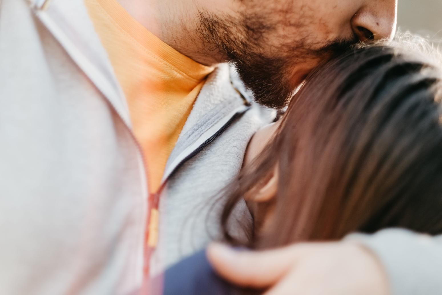 En una toma íntima y en primer plano, una persona besa la frente de otra, ambas vestidas con ropa informal.