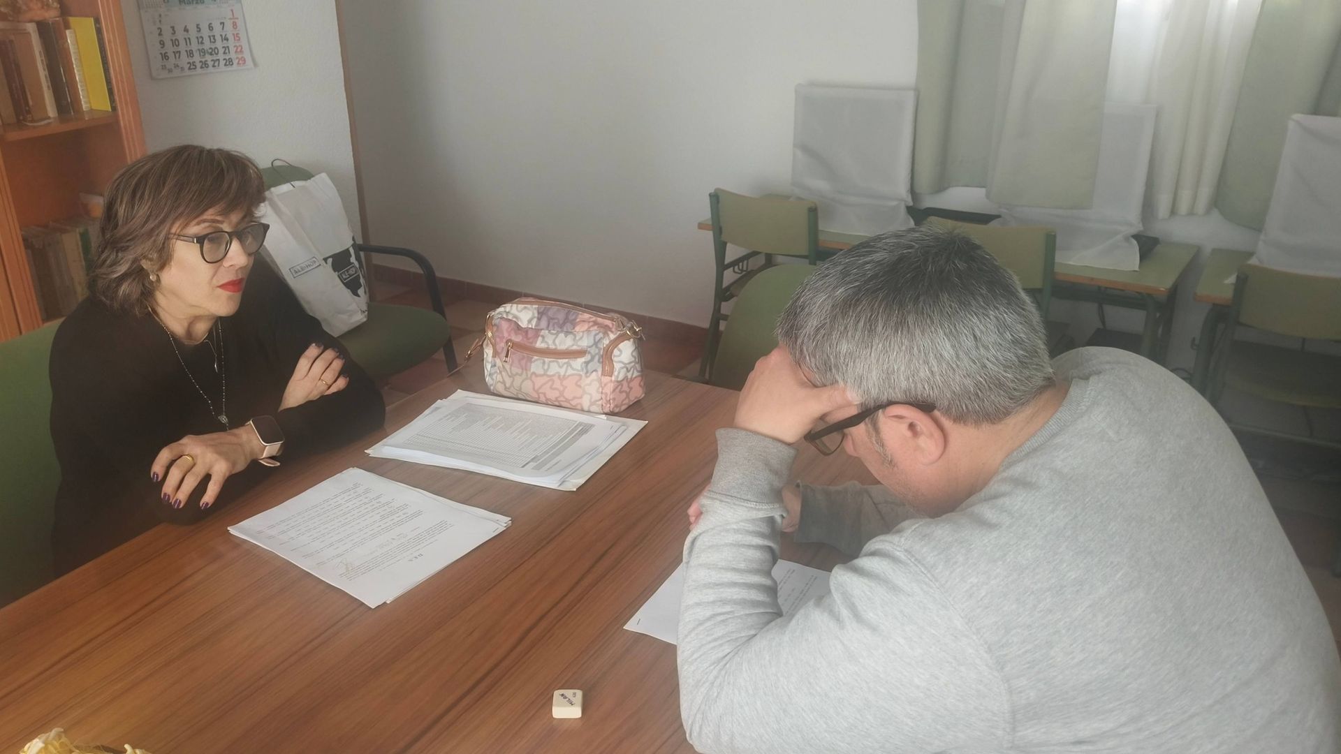 Dos personas están sentadas en un escritorio con documentos