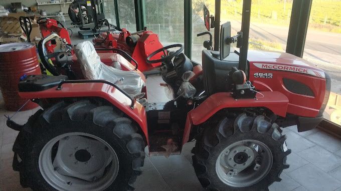 Un tractor rojo está estacionado en un garaje al lado de una ventana.