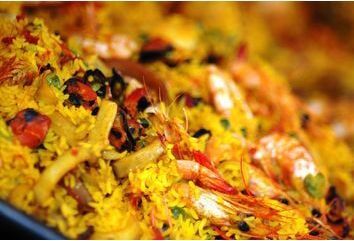 Detalhe de uma paella de frutos do mar vibrante com camarão, arroz e legumes.