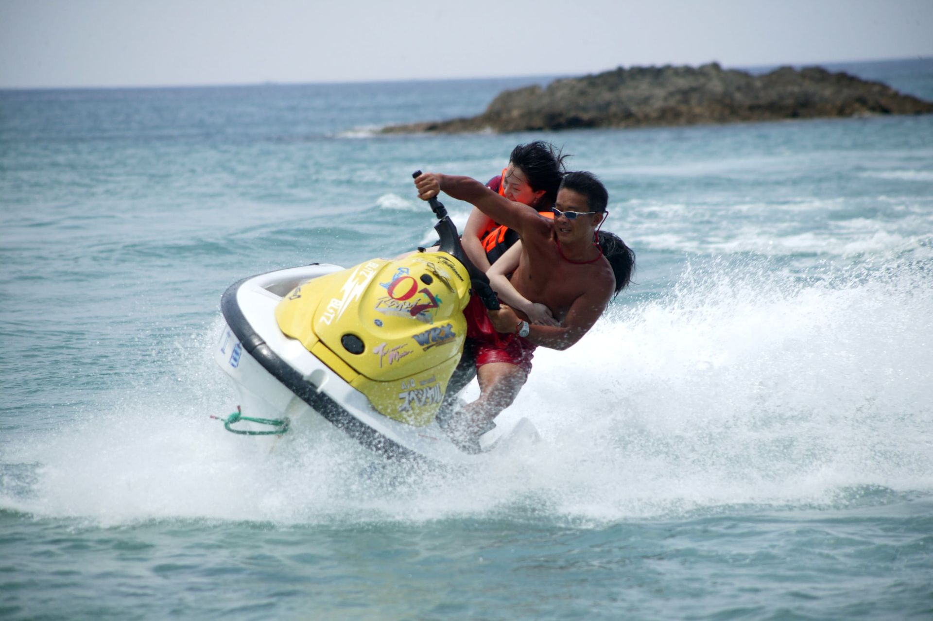 Dos personas viajan en una moto acuática en el océano.