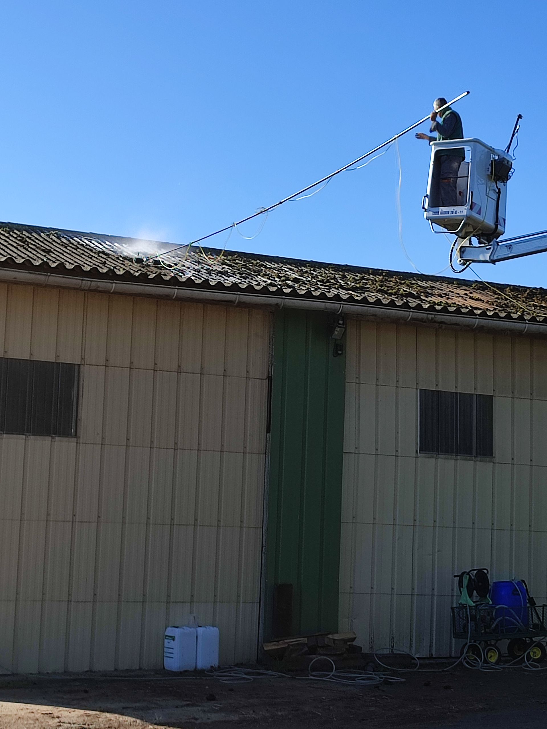 Des pompiers à bord d'une nacelle élévatrice éteignent un incendie sur le toit d'un bâtiment.