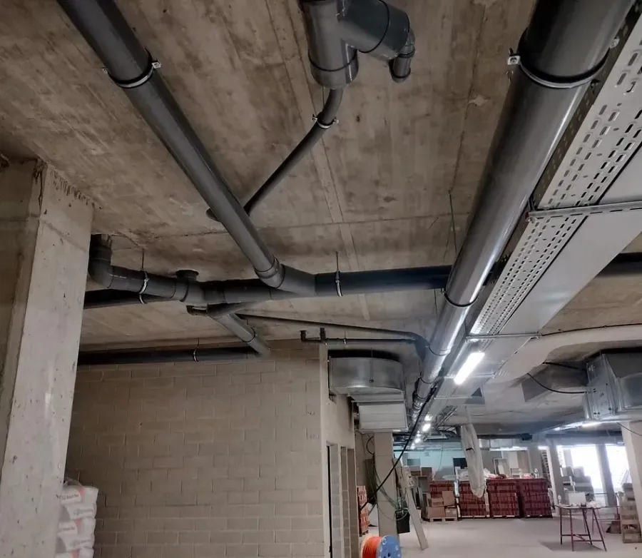 Tuberías suspendidas de un techo de hormigón en el interior de un edificio industrial o comercial.