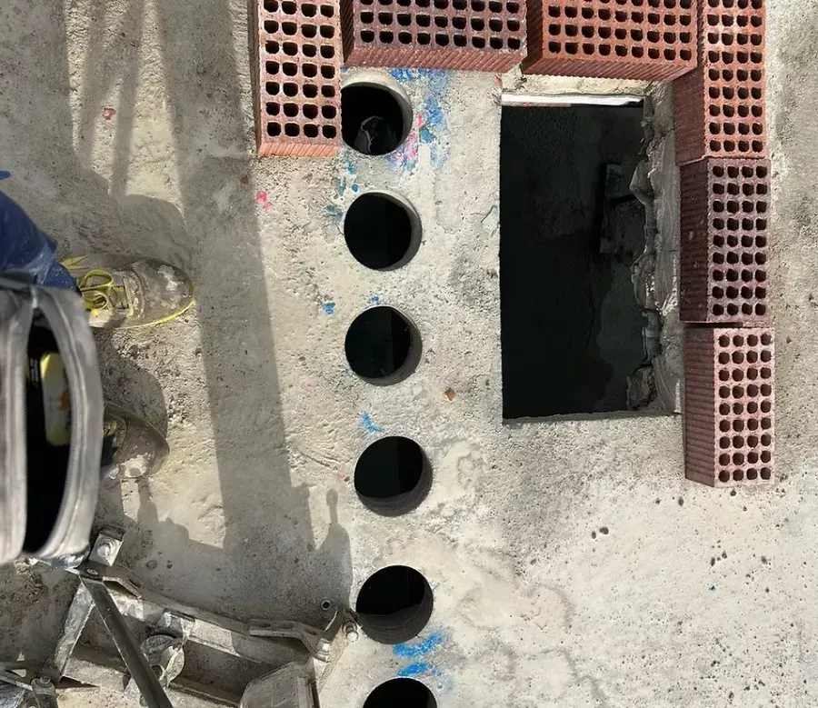 Una losa de hormigón que muestra una hilera de agujeros circulares perforados junto a un recorte rectangular.