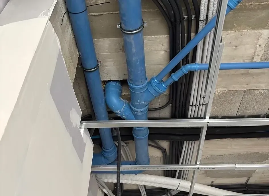 Tuberías de agua azules a la vista instalado a lo largo de un techo de hormigón y una estructura metálica.