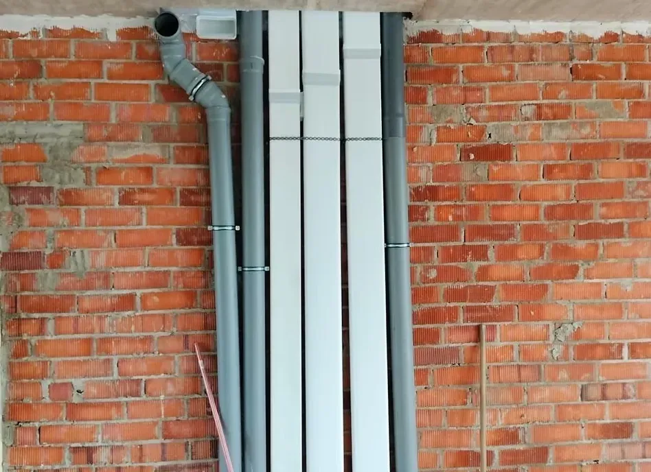 Varias tuberías circulares grises y rectangulares blancas discurren verticalmente.