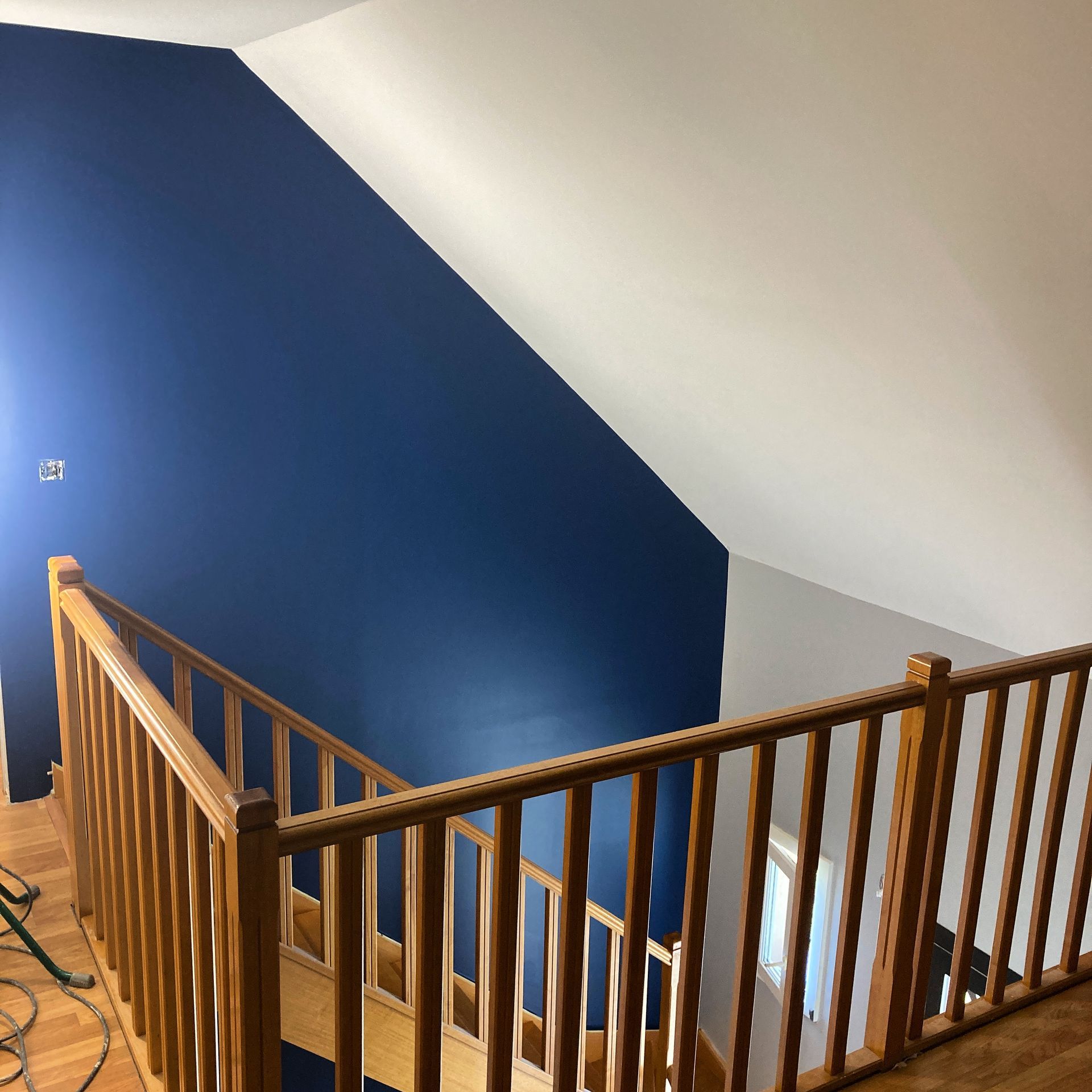Escalier avec rambarde en bois, mur bleu et un plafond blanc.