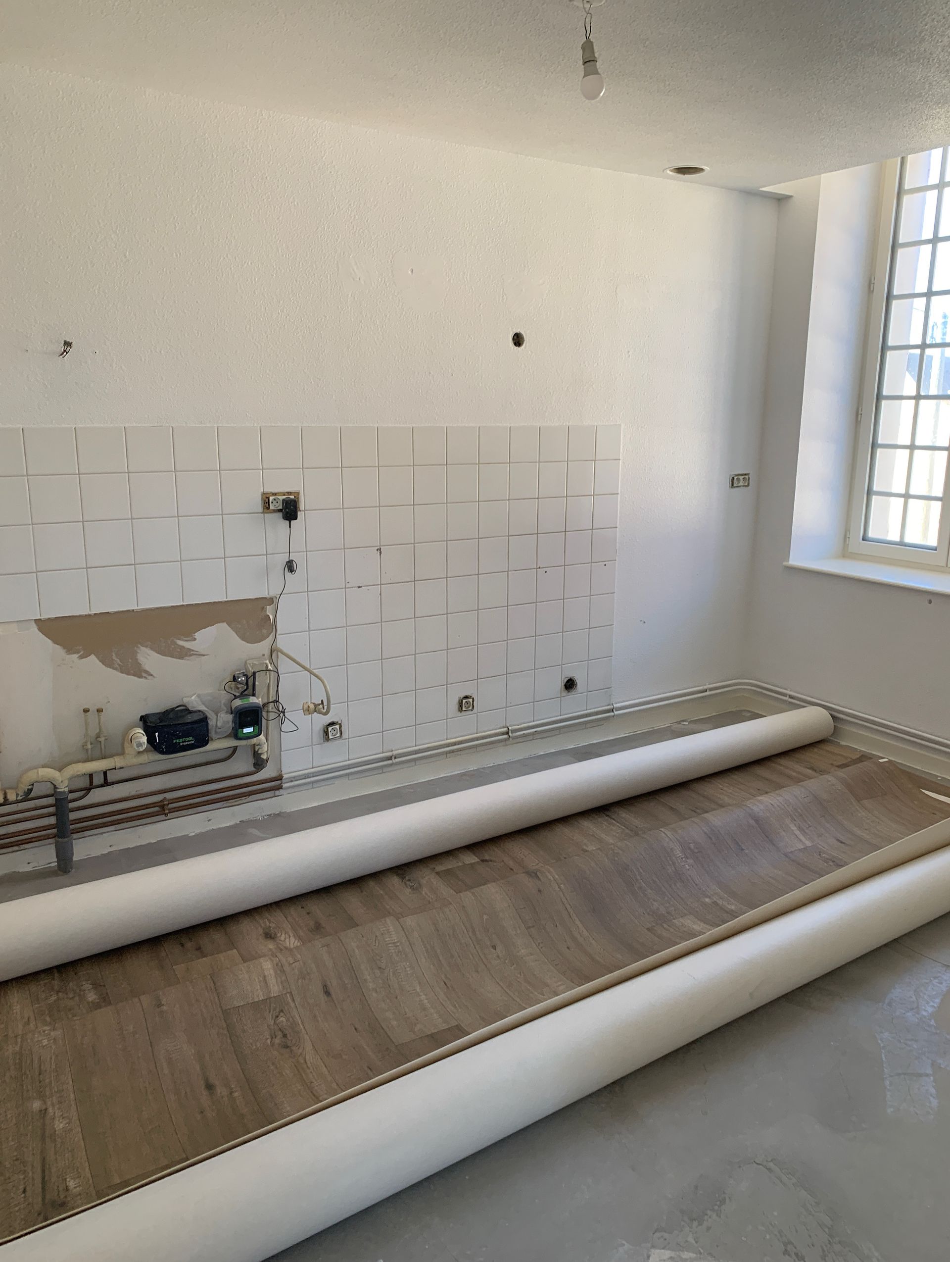 Cuisine vide avec crédence, revêtement de sol et fenêtre partiellement installés.