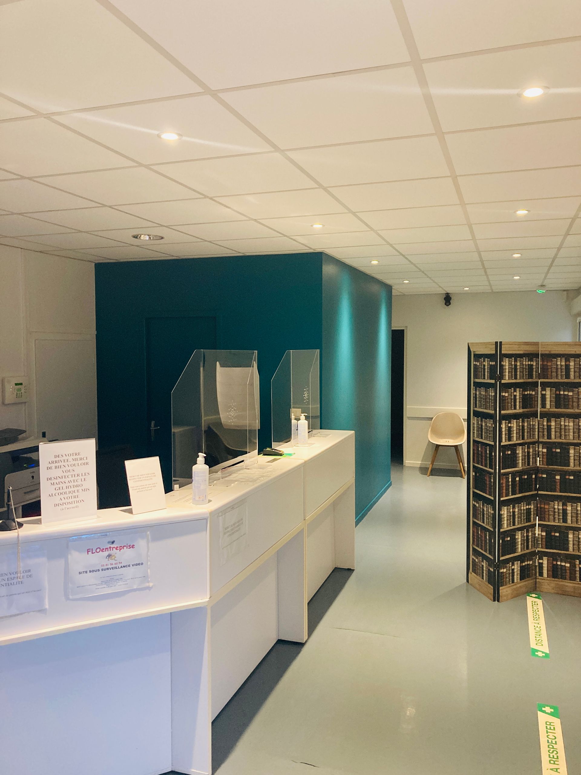 Un comptoir d'accueil avec une bibliothèque visible sur la droite.