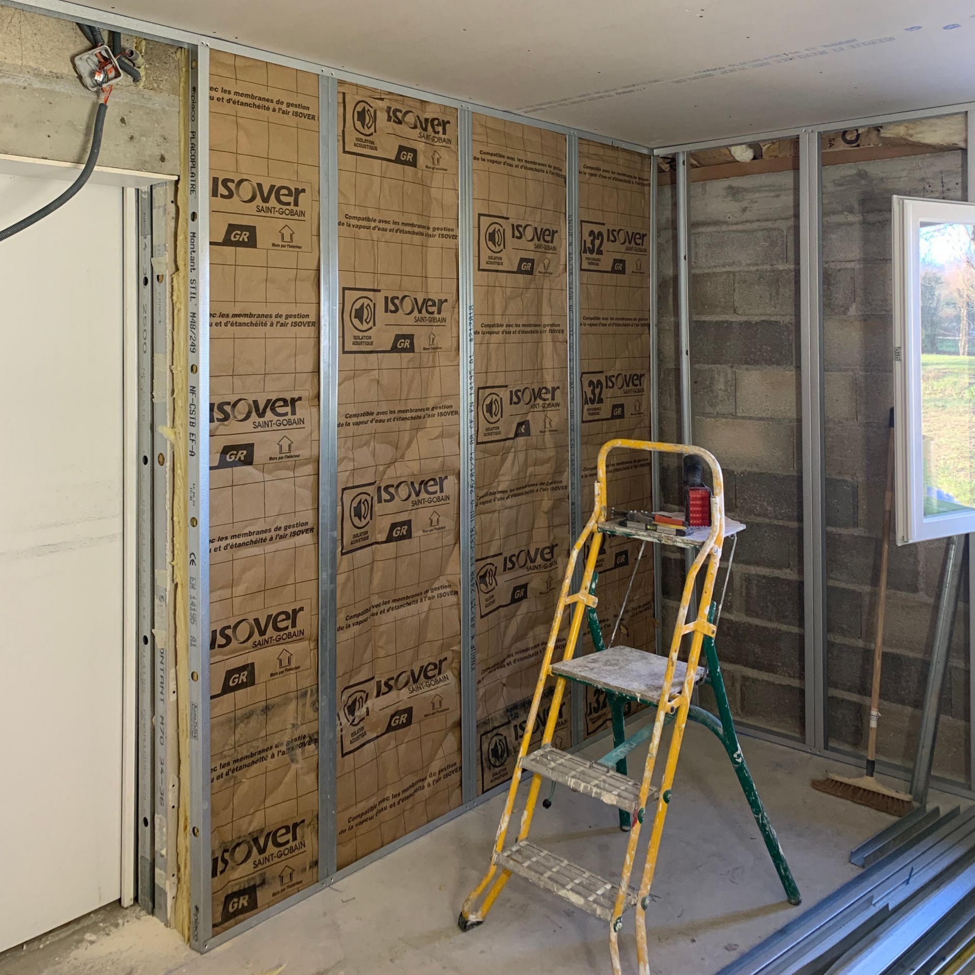 Aménagement intérieur avec isolation et ossature métallique sur murs.