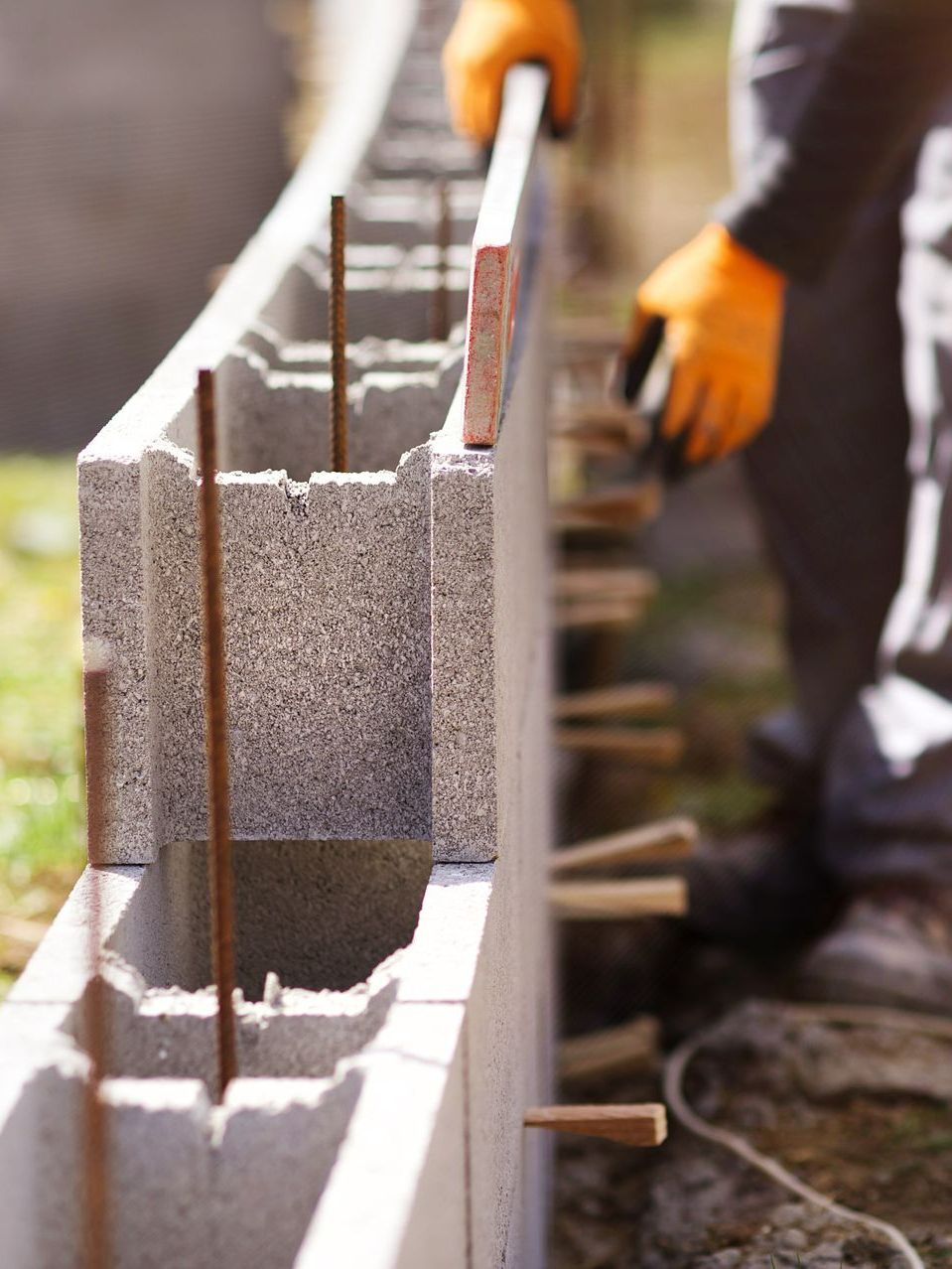 Un maçon qui construit un mur de clôture à l'aide de parpaings