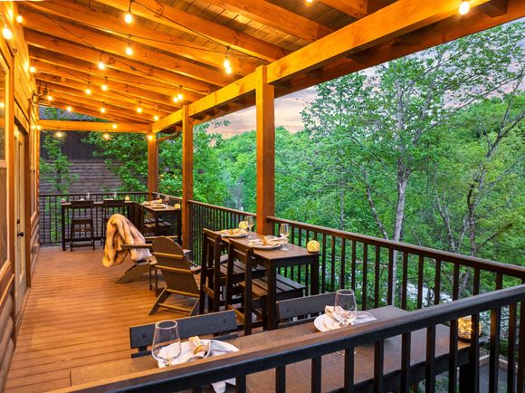 There is a large deck with tables and chairs on it.
