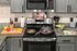 A kitchen with a stove , microwave , and cutting board.