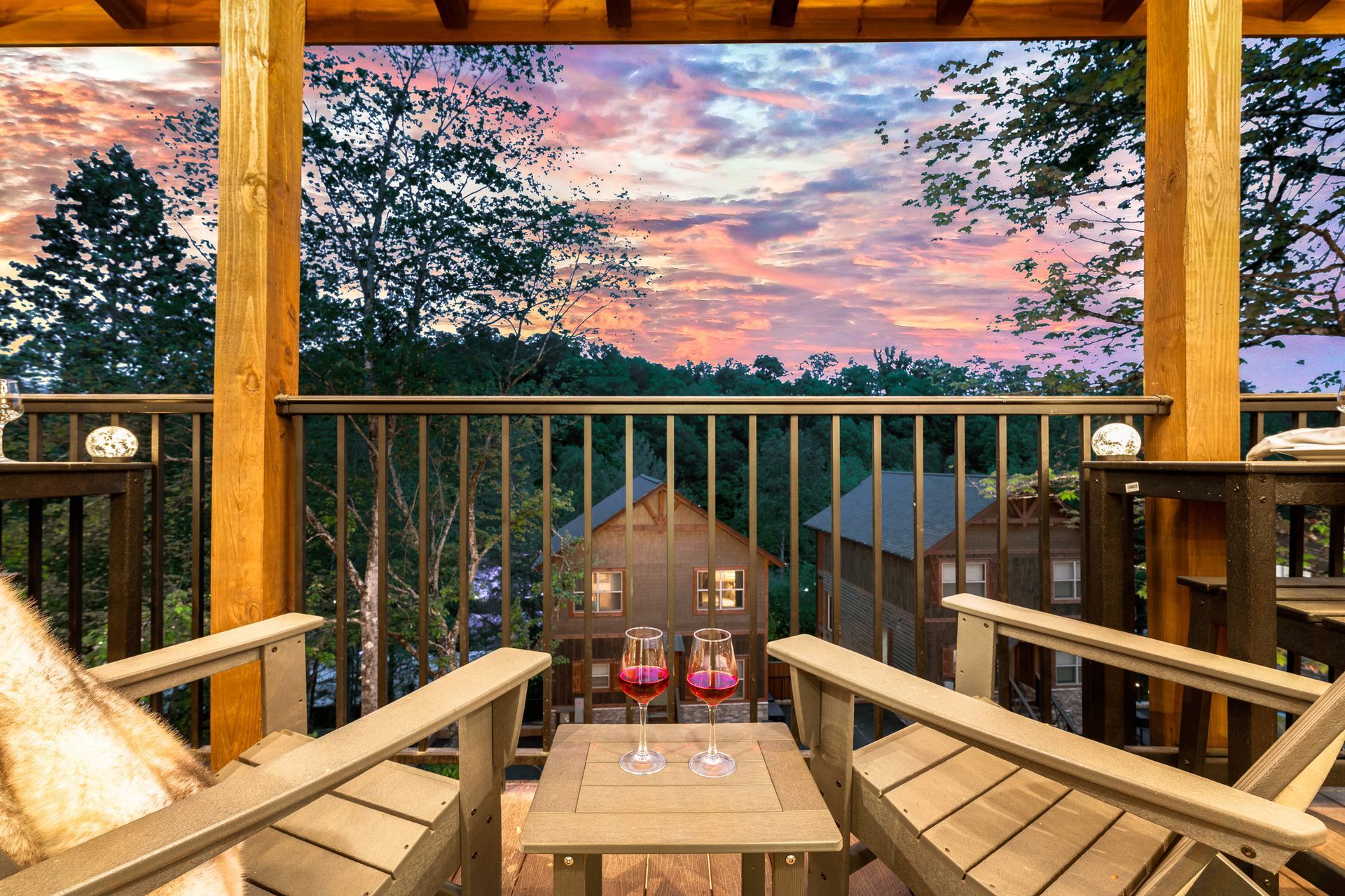 A balcony with two chairs and a table with a view of a sunset.