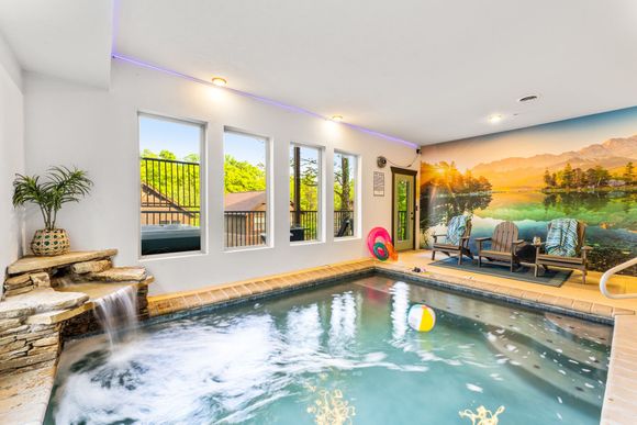 A large indoor swimming pool with a waterfall and a mural on the wall.