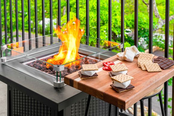 A fire pit with s'mores and crackers on a cutting board on a balcony.