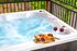 A hot tub with a tray of food and two glasses of wine in it.