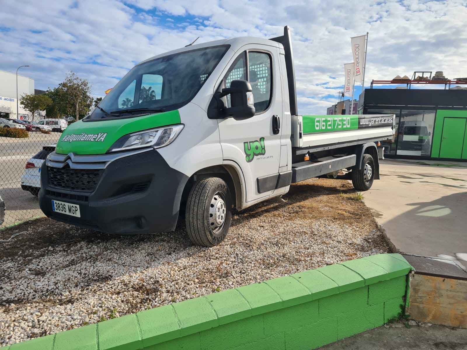 Una grúa blanca y verde está estacionada al lado de una pared verde.